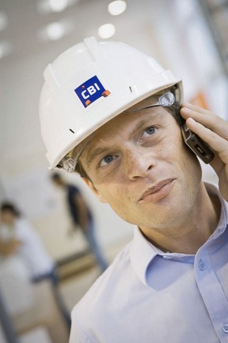 Photo de portrait corporate d'un homme caqué sur chantier au téléphone. Photo de reportage réalisée pour l'entreprise CBI. | Philippe DUREUIL Photographie