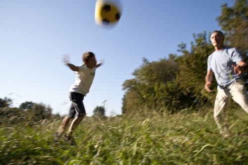 Enfant qui joue au ballon avec son père dans un parc | Philippe DUREUIL Photographie