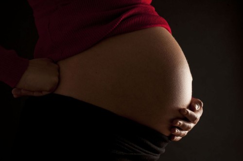 Femme enceinte photographiée de profil à contre-jour, elle soutient son ventre avec sa main gauche. | Philippe DUREUIL Photographie